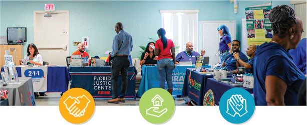 row of informational tables with people standing and asking questions